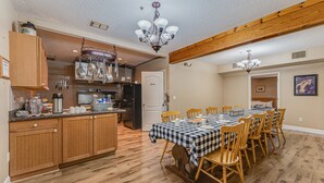 A spacious kitchen with wooden cabinets, a central island, and a dining area with a checkered tablecloth and wooden chairs. - The Chassahowitzka Hotel (Homosassa)