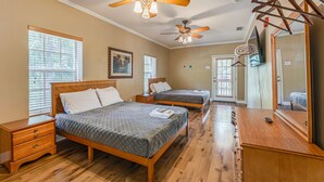 A bedroom with two beds, wooden floors, ceiling fans, a wooden dresser, and a mirror. - The Chassahowitzka Hotel (Homosassa)
