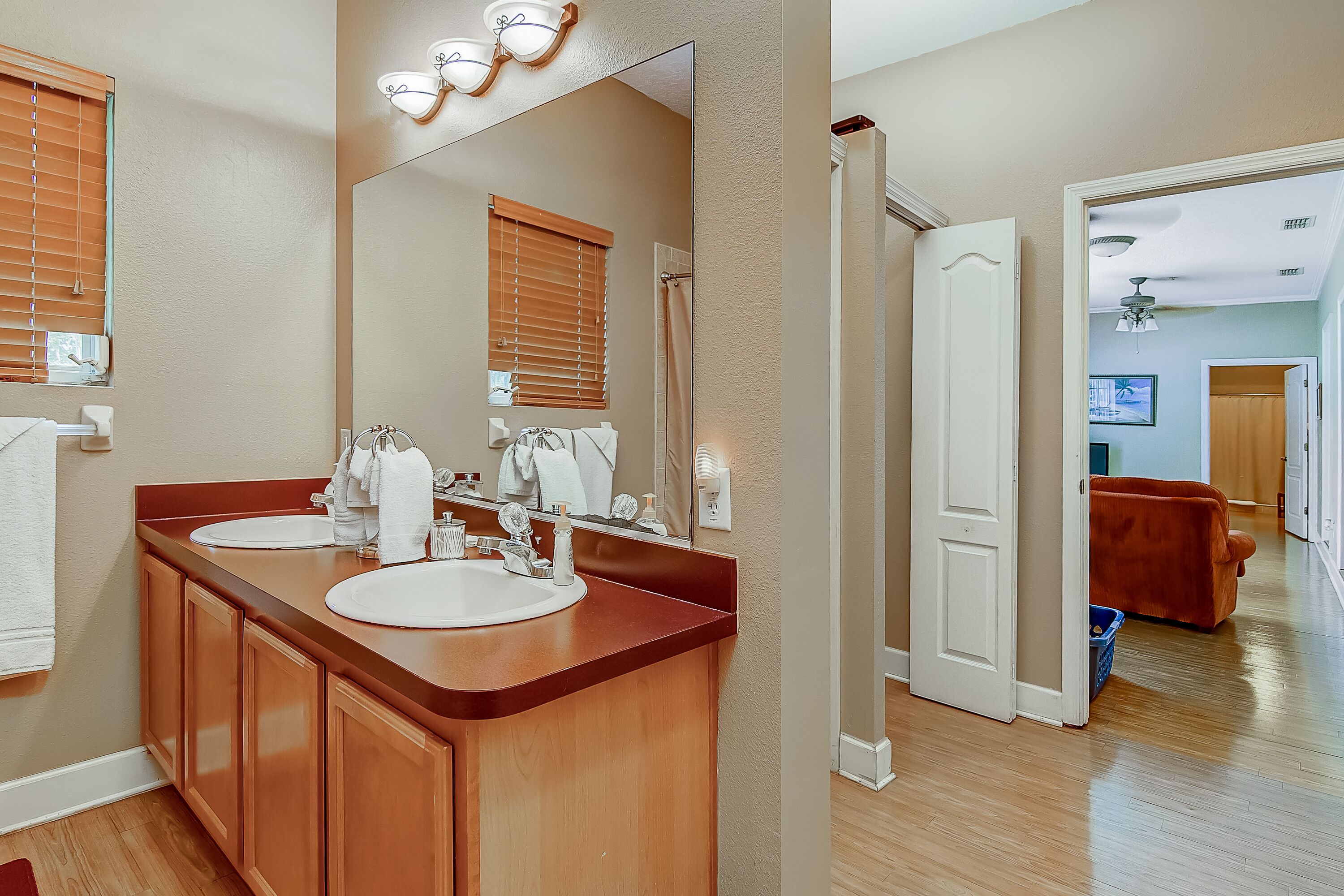A bathroom with a double sink vanity, a large mirror, and a shower area.