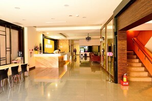 A hotel lobby with a reception desk, a dining area with chairs, a staircase, and a fire extinguisher. - Kaishen Hotel (Taitung)