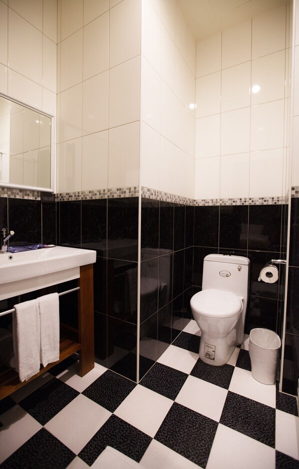 A bathroom with a black and white checkered floor, a white sink, a mirror, and a toilet.