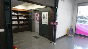 Aula, jossa on lasiseinä, palosammutin, ilmoitustaulu ja opastekyltti.