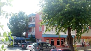 Ein Parkplatz mit mehreren Autos, ein Gebäude mit Balkonen und ein Baum im Vordergrund.