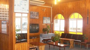 Ein gemütliches Zimmer mit Holzwänden, einem Fernseher, einer Karte und einem Tisch mit Stühlen.