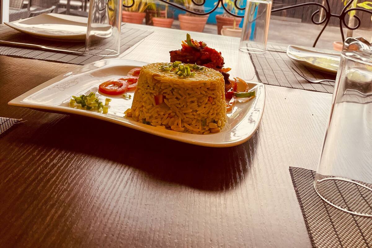 A table with a plate of food, a glass pitcher, and a decorative metal fence in the background.