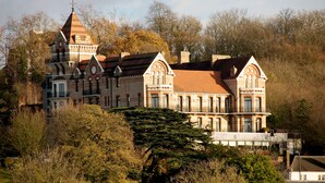Un grand bâtiment historique doté de nombreuses tours, dont une tour centrale particulièrement imposante.