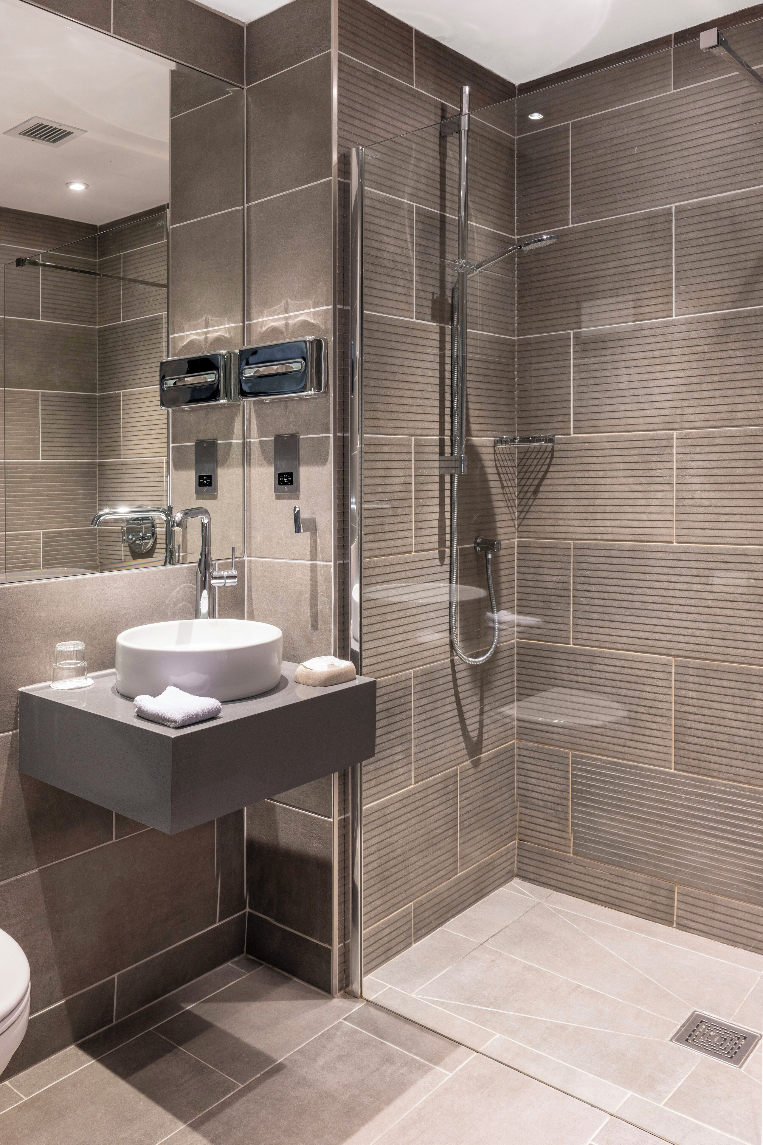 A modern bathroom with a built-in sink, a shower with a handheld showerhead, and a toilet.
