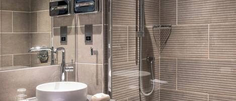 A modern bathroom with a built-in sink, a shower with a handheld showerhead, and a toilet.