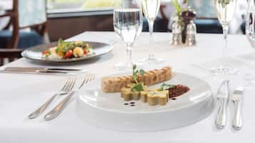 A dining table with a white tablecloth, silverware, and a plate of food.