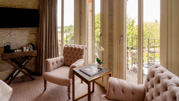 Un salon spacieux doté d’une grande fenêtre, d’un fauteuil confortable, d’un canapé et d’une petite table agrémentée d’un objet décoratif.