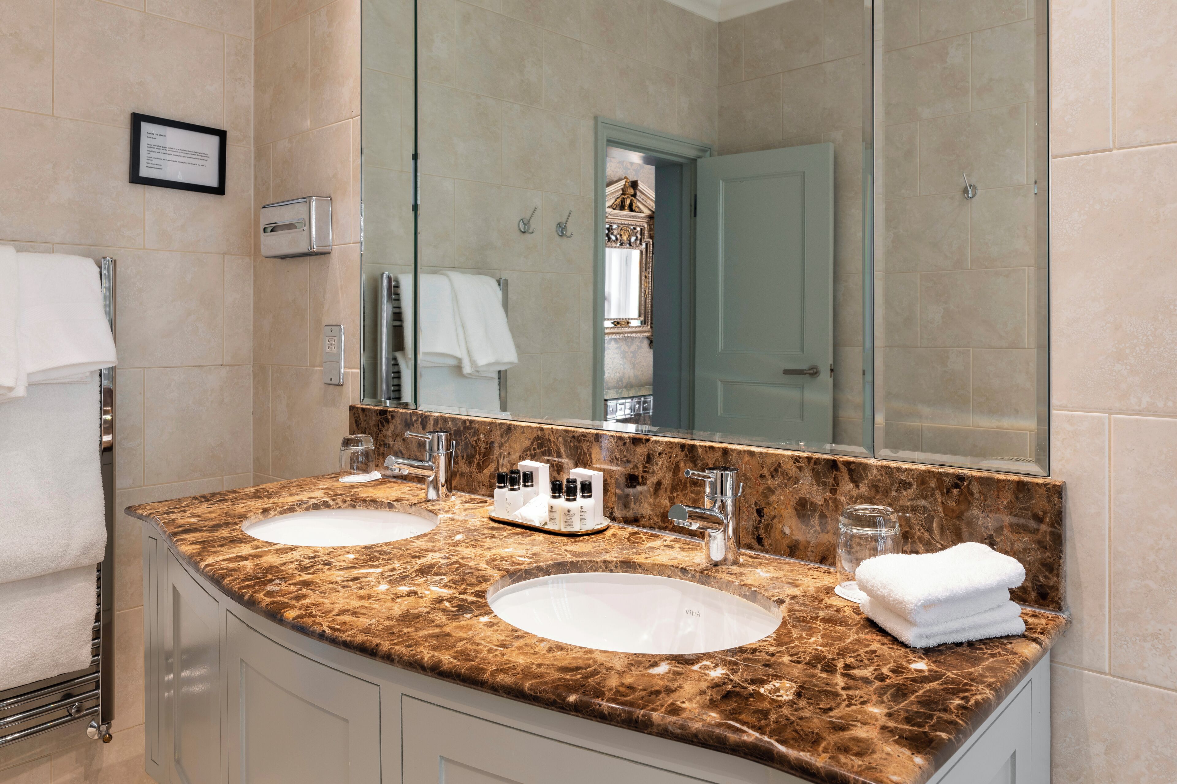 A bathroom with two sinks, a large mirror, and a towel rack.