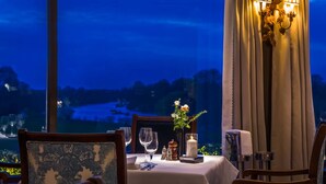 Une table dressée pour le dîner, avec une bougie et un vase de fleurs, donnant sur un paysage magnifique.