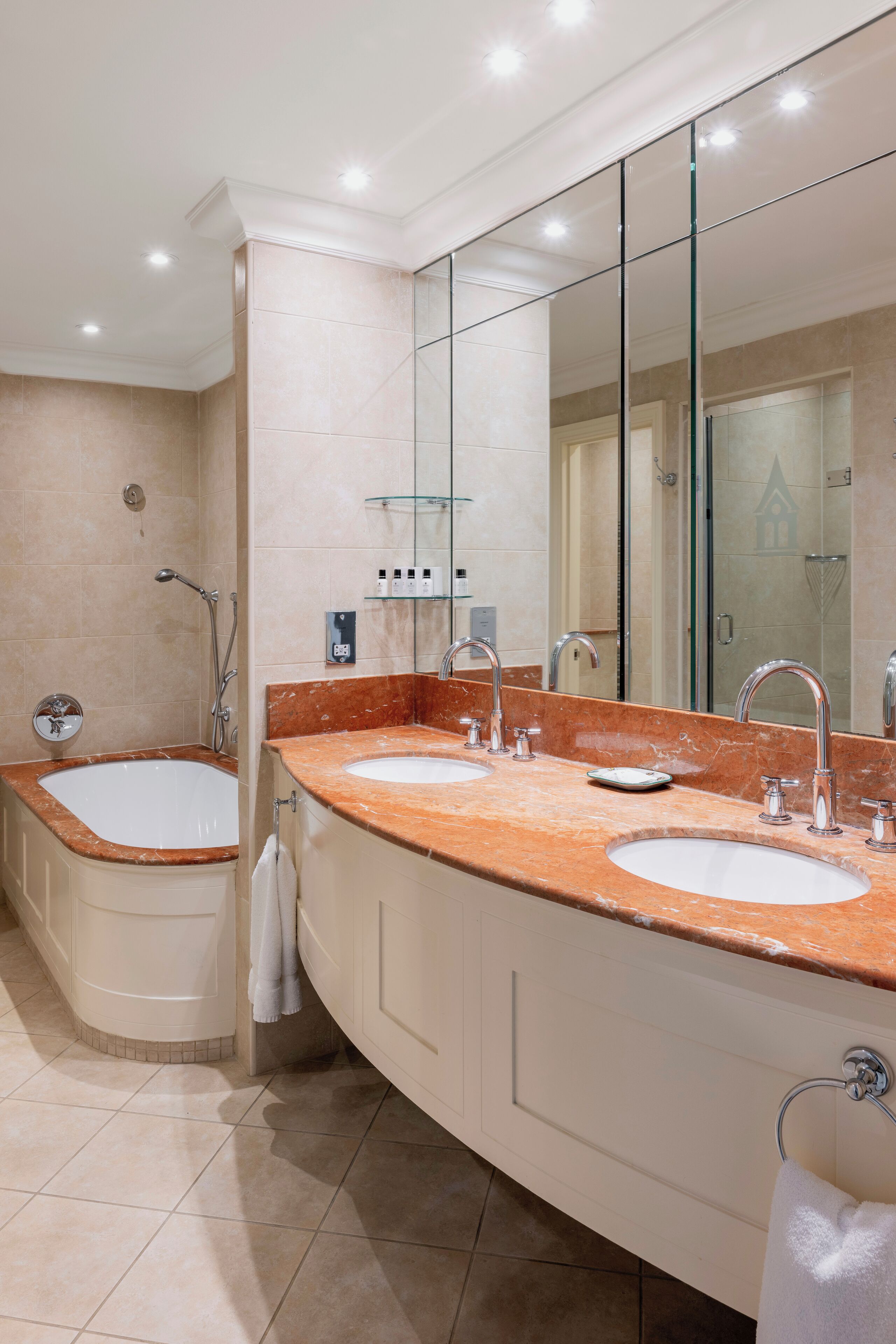 Une salle de bain moderne avec deux lavabos, un grand miroir et une douche à l’italienne.