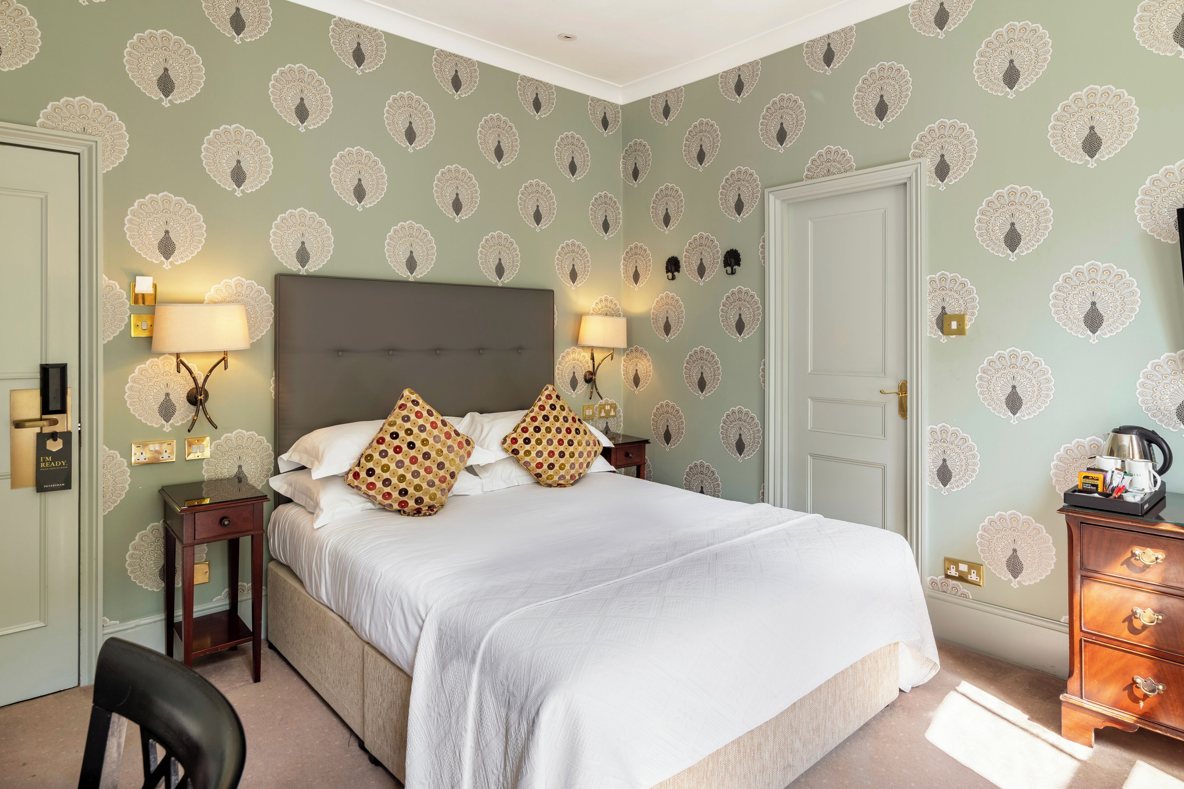 A neatly arranged bedroom with a large bed, two bedside tables with lamps, a dresser, and a chair.