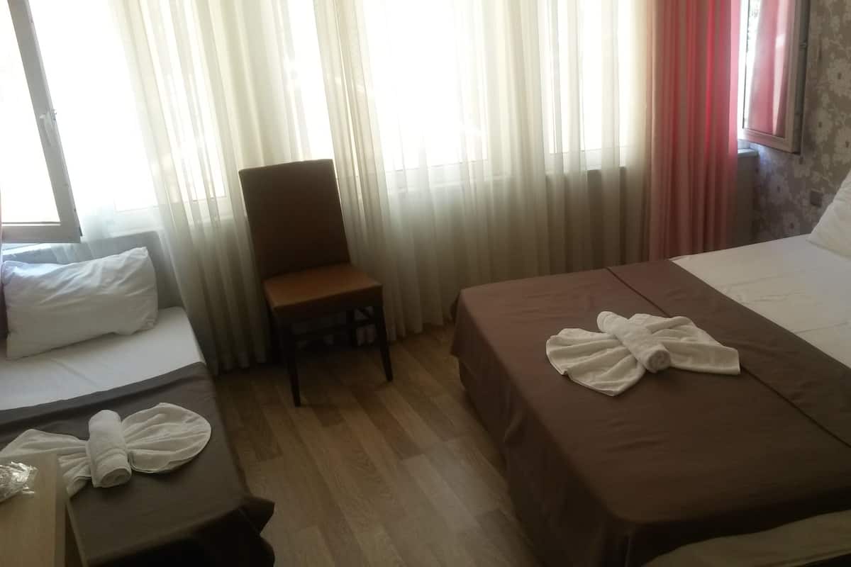 A hotel room with a bed, a chair, a small table with a towel, and curtains.