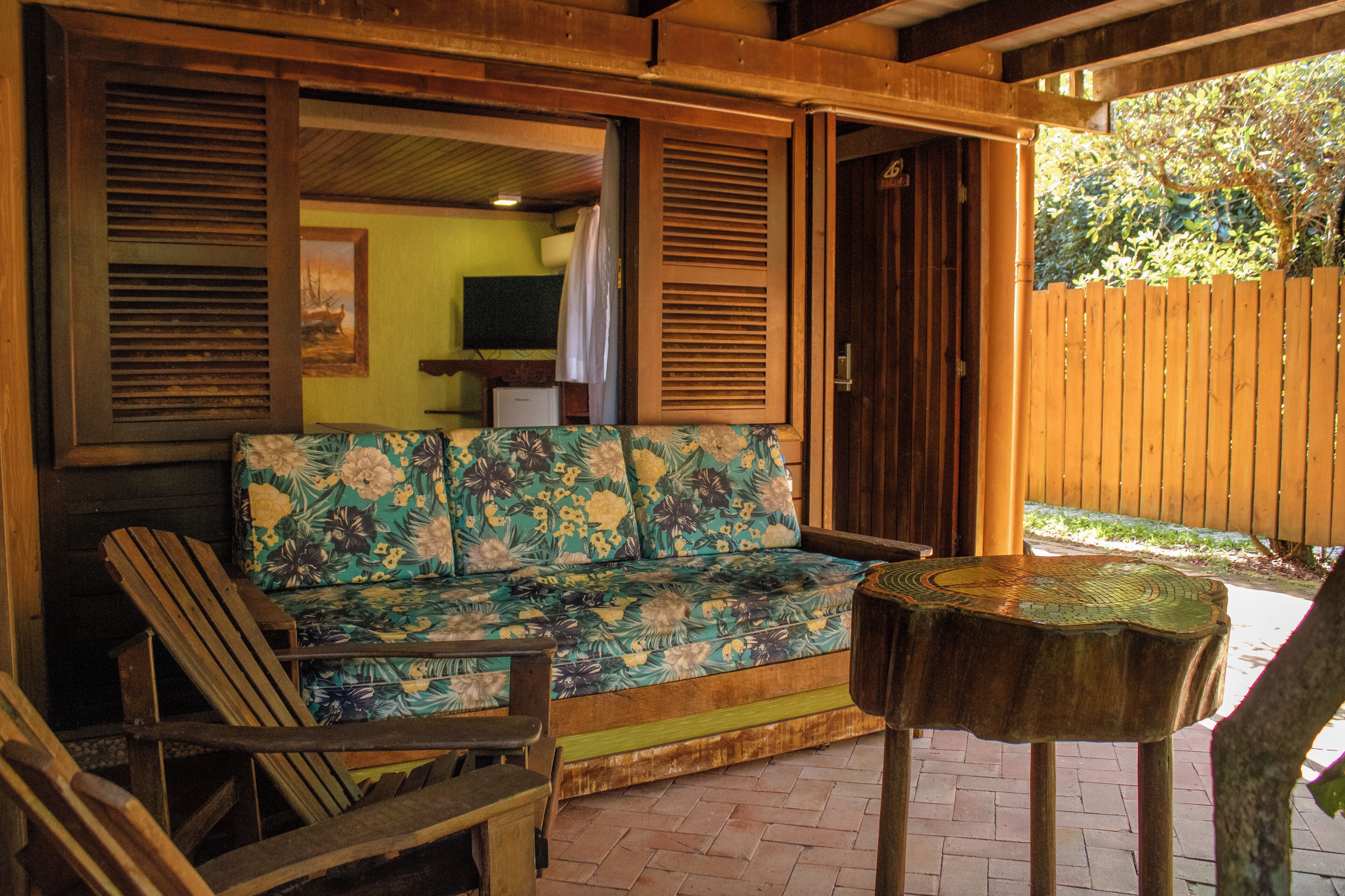 A wooden deck with a sofa and chairs, a small table, and a wooden fence.