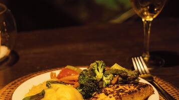 A plate of food with a glass of white wine on a table.