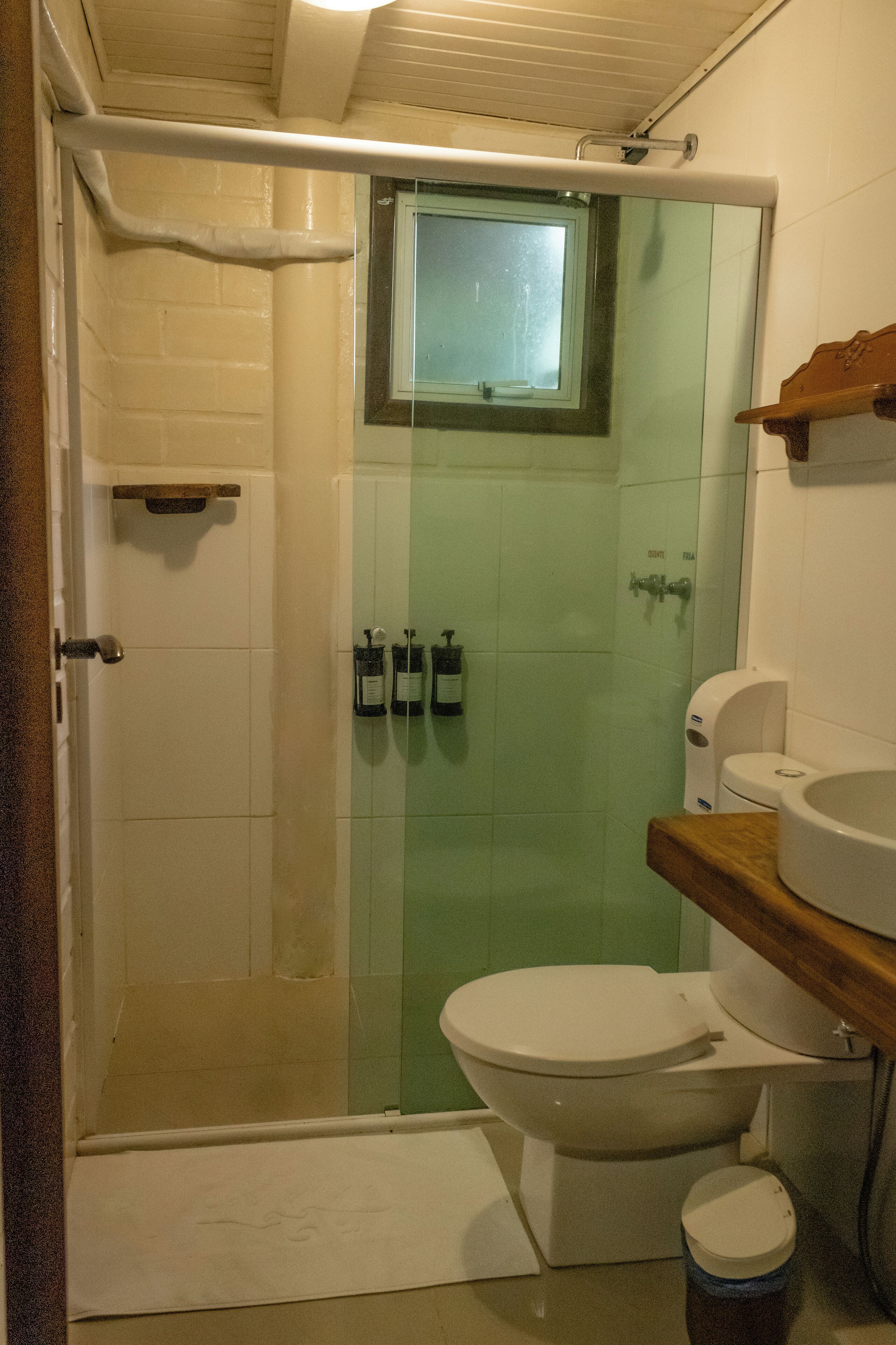 A bathroom with a glass shower enclosure, a toilet, and a sink.