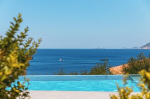 Una piscina al aire libre, sombrillas, sillones reclinables de piscina