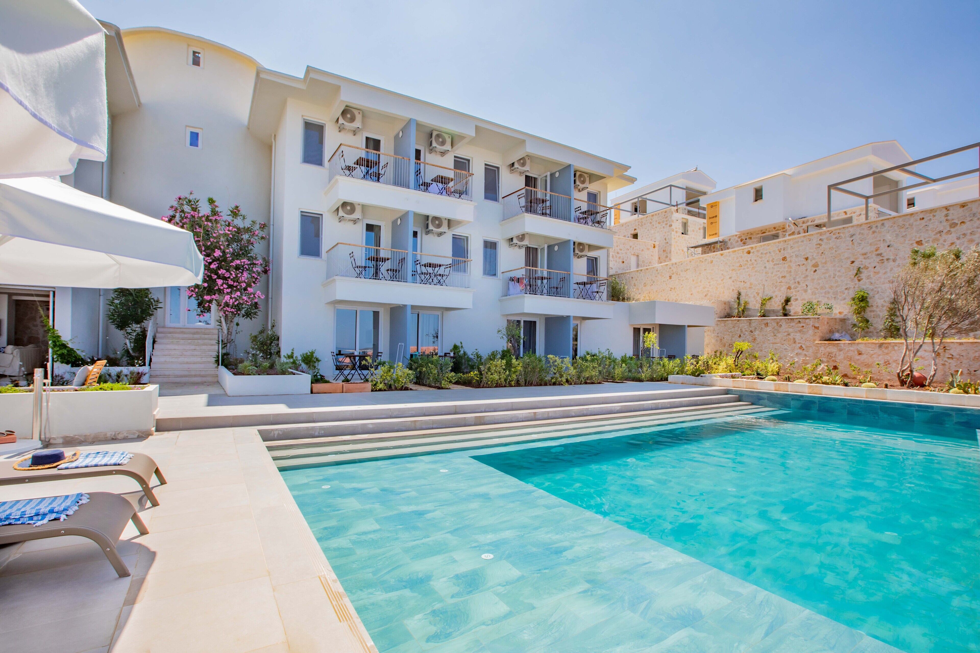 Un hôtel moderne doté d’une piscine, de nombreux balcons et d’un espace extérieur aménagé pour se détendre.