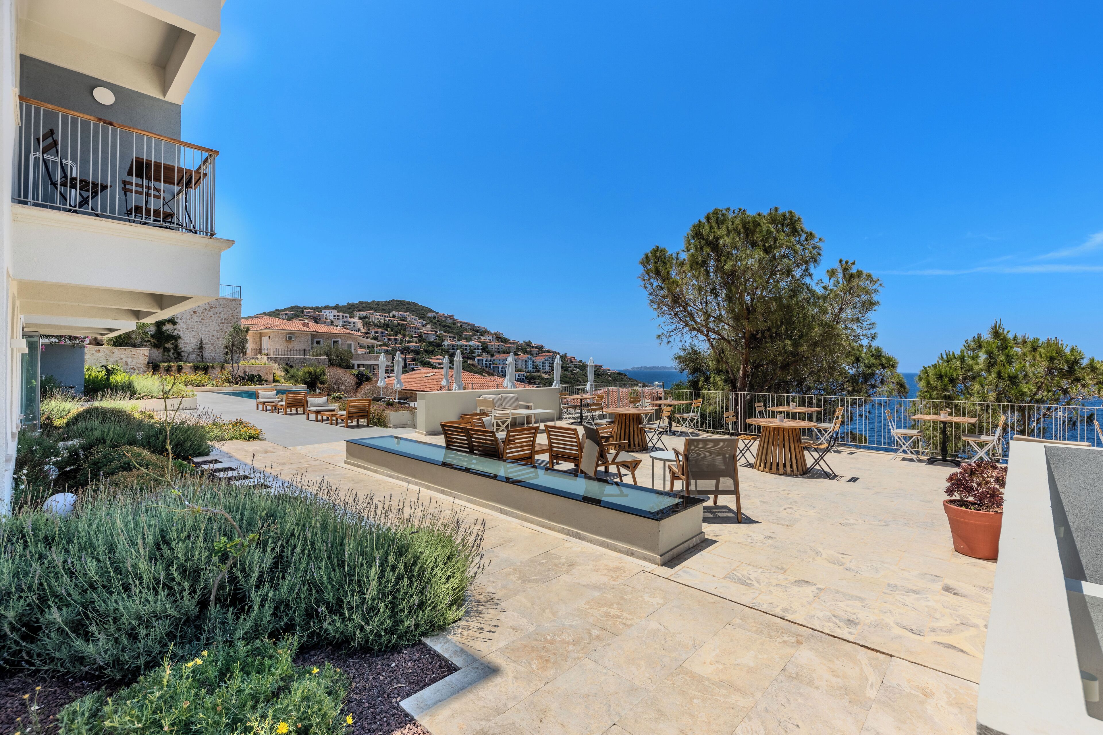 A rooftop terrace with outdoor seating, a swimming pool, and a view of the sea.