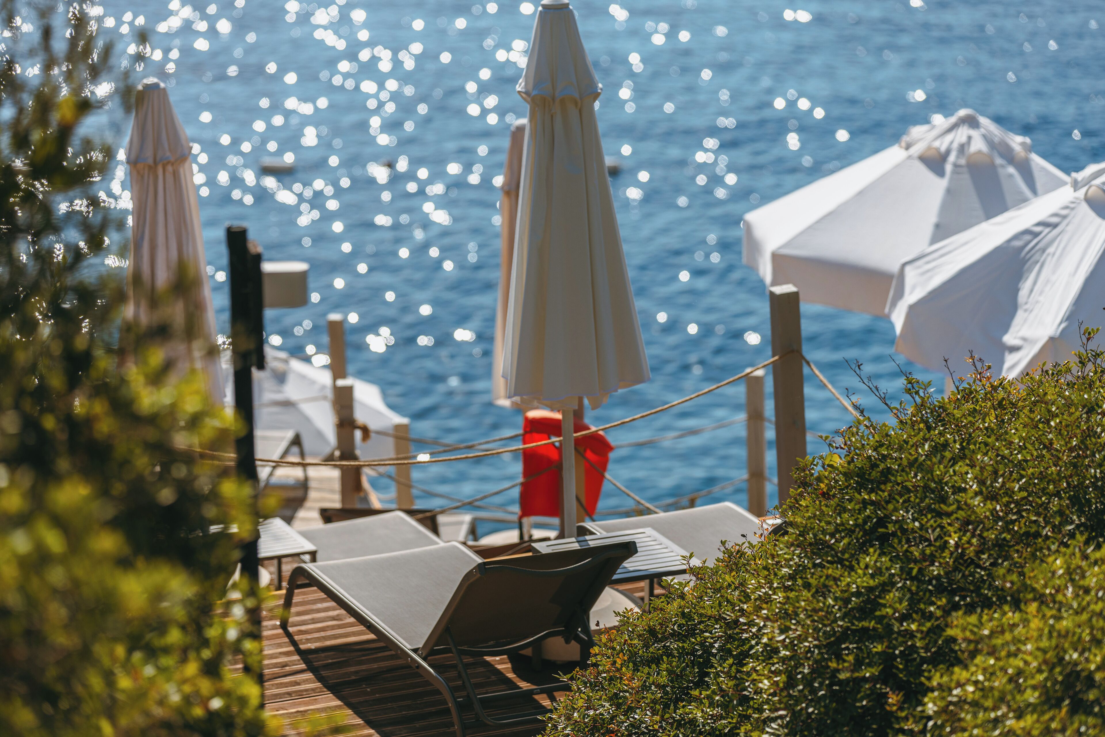 A deck with lounge chairs and umbrellas overlooking the sea.