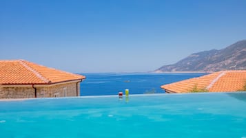 Una piscina al aire libre, sombrillas, sillones reclinables de piscina