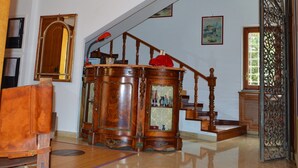 Une pièce spacieuse avec un escalier en bois, une grande armoire en bois et un miroir au mur.