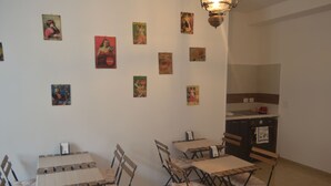 Un espace repas avec une table et des chaises, un coin cuisine avec des placards et un évier, ainsi que divers éléments de décoration murale.