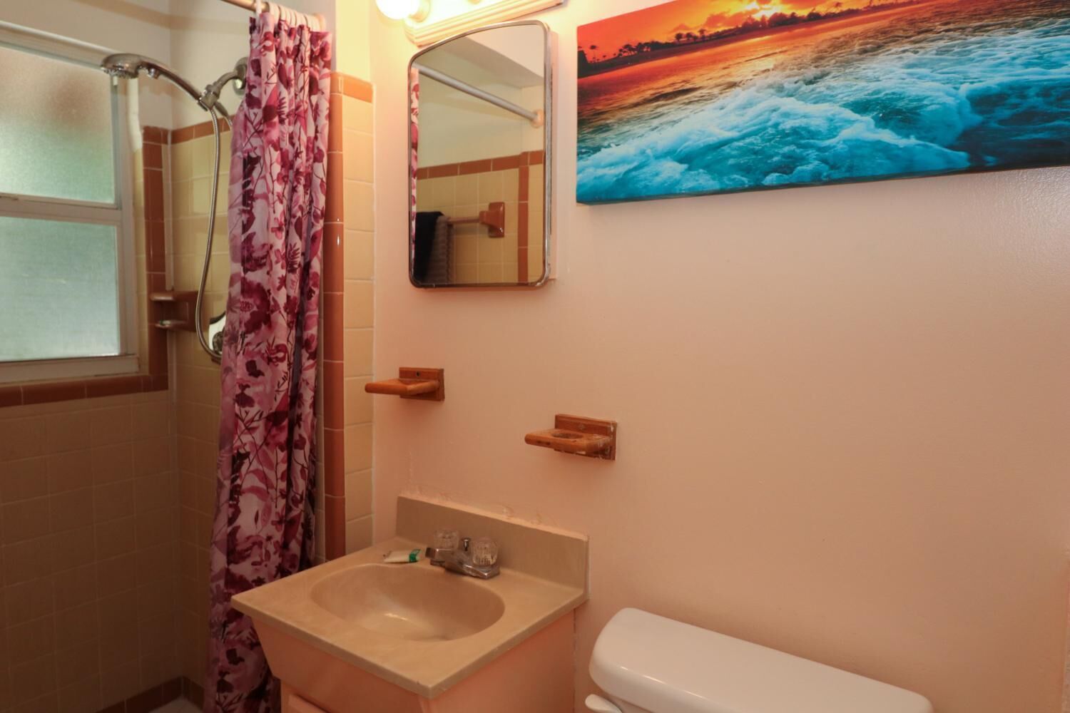 Une salle de bain équipée d’une douche, d’un lavabo, de toilettes et d’un miroir.