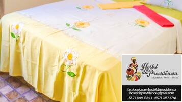A neatly made bed with floral bedding, a bedside table with a lamp, and a wall-mounted mirror.