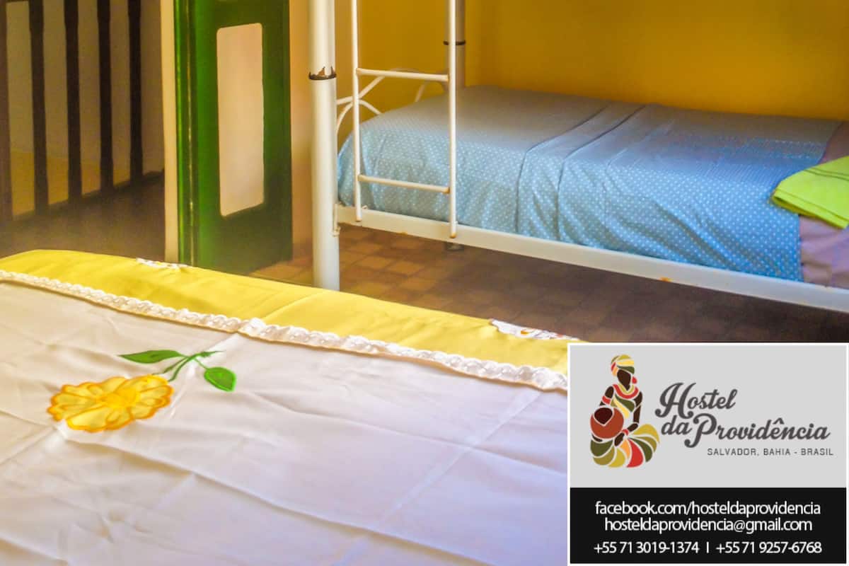 A bunk bed room with a green door, yellow walls, and a bedspread with a floral design.