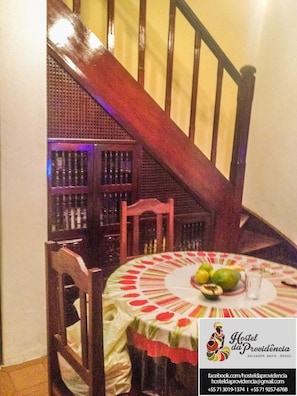 A dining area with a round table, chairs, and a staircase in the background. - Hostel da Providencia (Salvador)