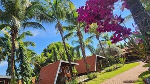 A tropical resort with palm trees, a brick pathway, and wooden cabins. - Pousada Monte Carlo (Olímpia)