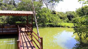 Uma ponte de madeira sobre um lago, com uma área coberta à esquerda.