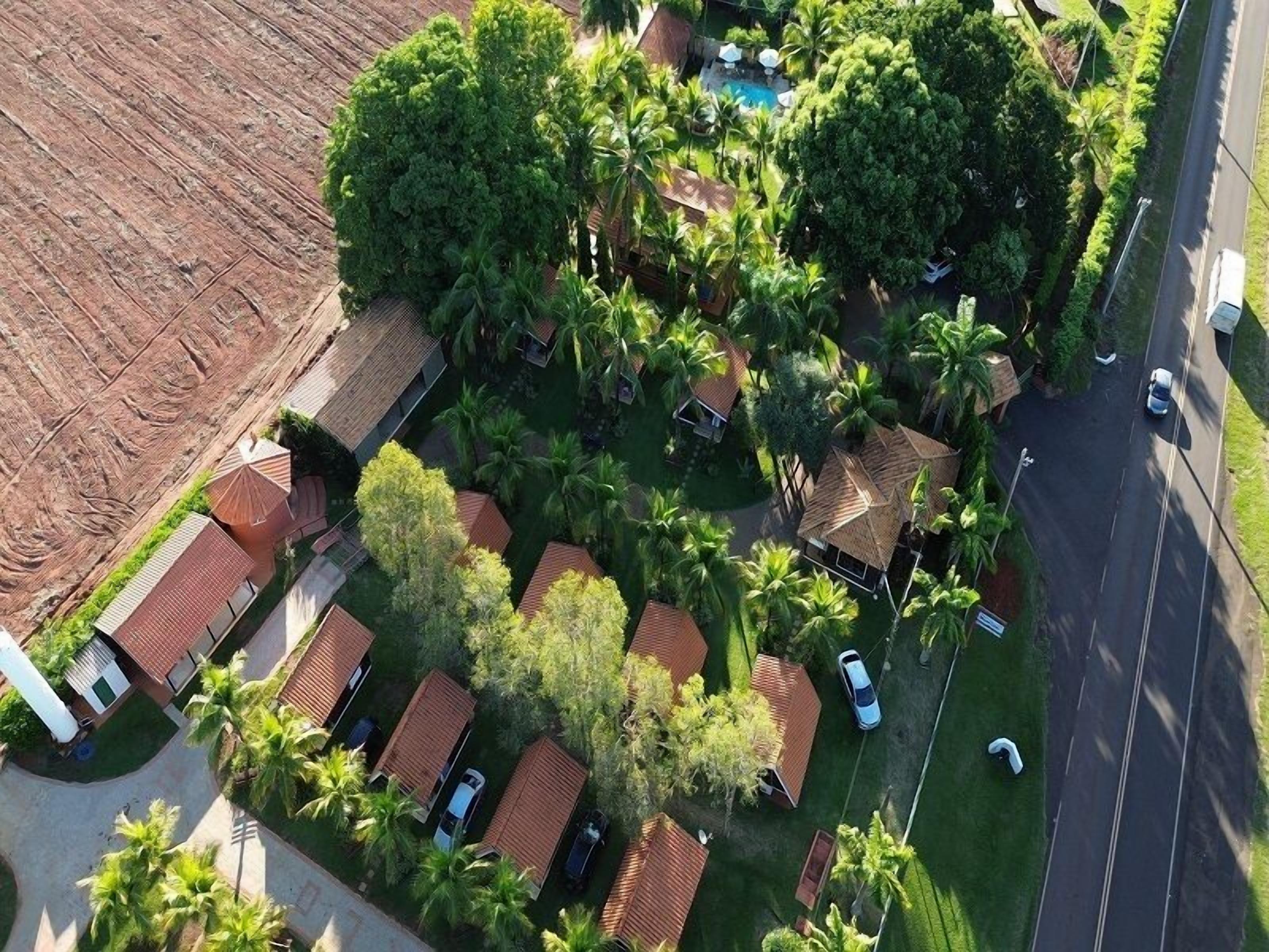 An aerial view of a residential area with multiple houses, a swimming pool, and a road.