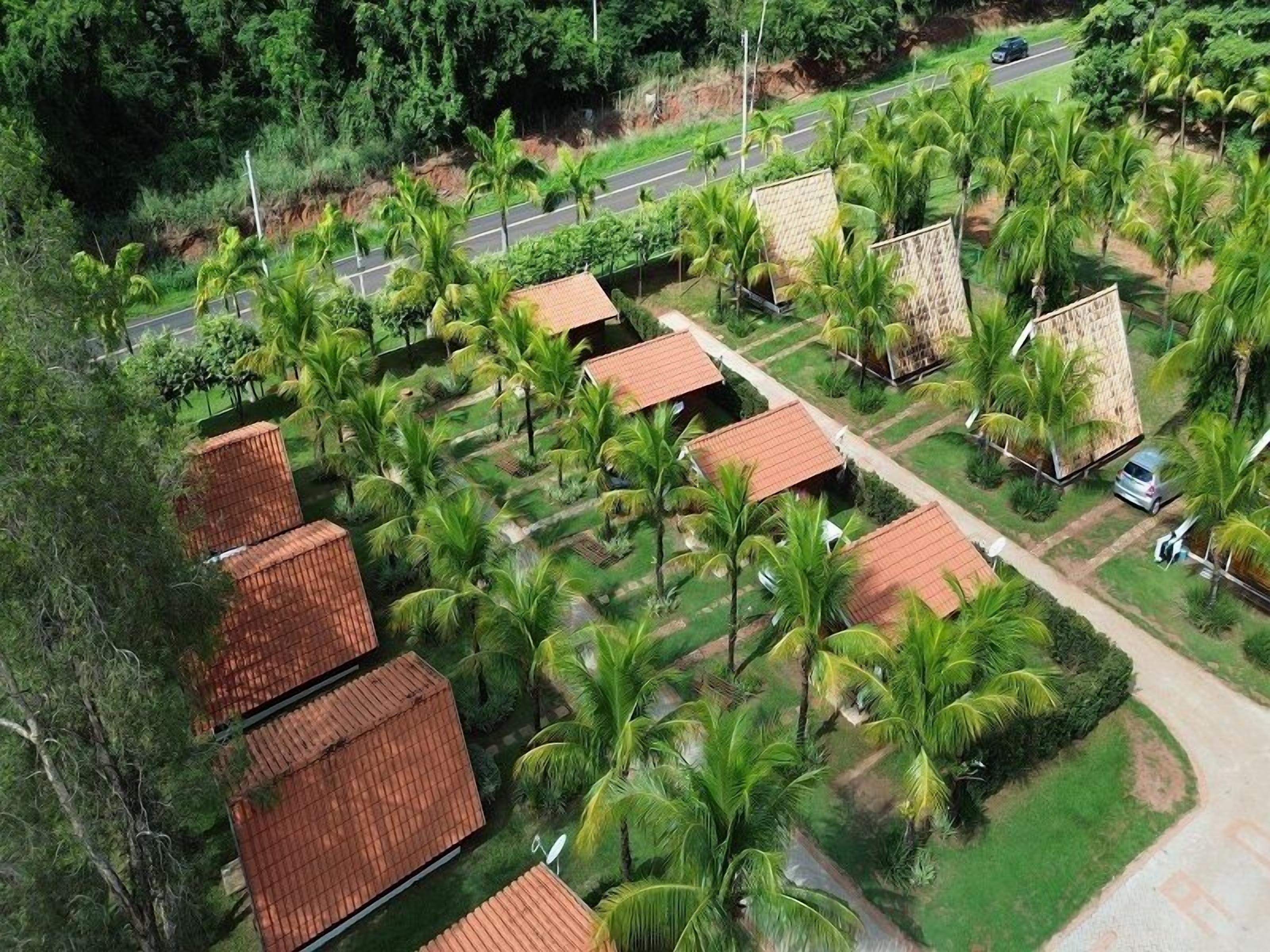 A residential area with multiple houses, each with a tiled roof, surrounded by lush greenery and palm trees.