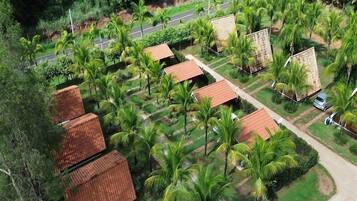 A residential area with multiple houses, each with a tiled roof, surrounded by lush greenery and palm trees.