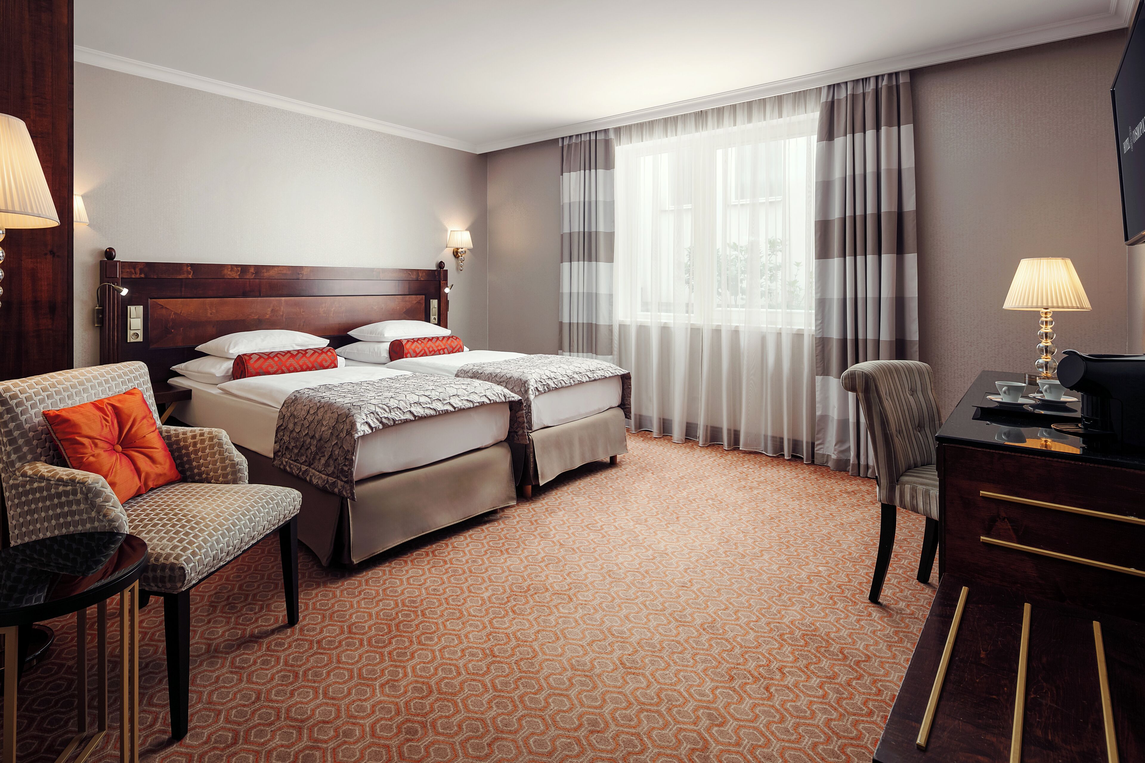 A hotel room with a double bed, two bedside tables, a desk, a chair, and a TV.