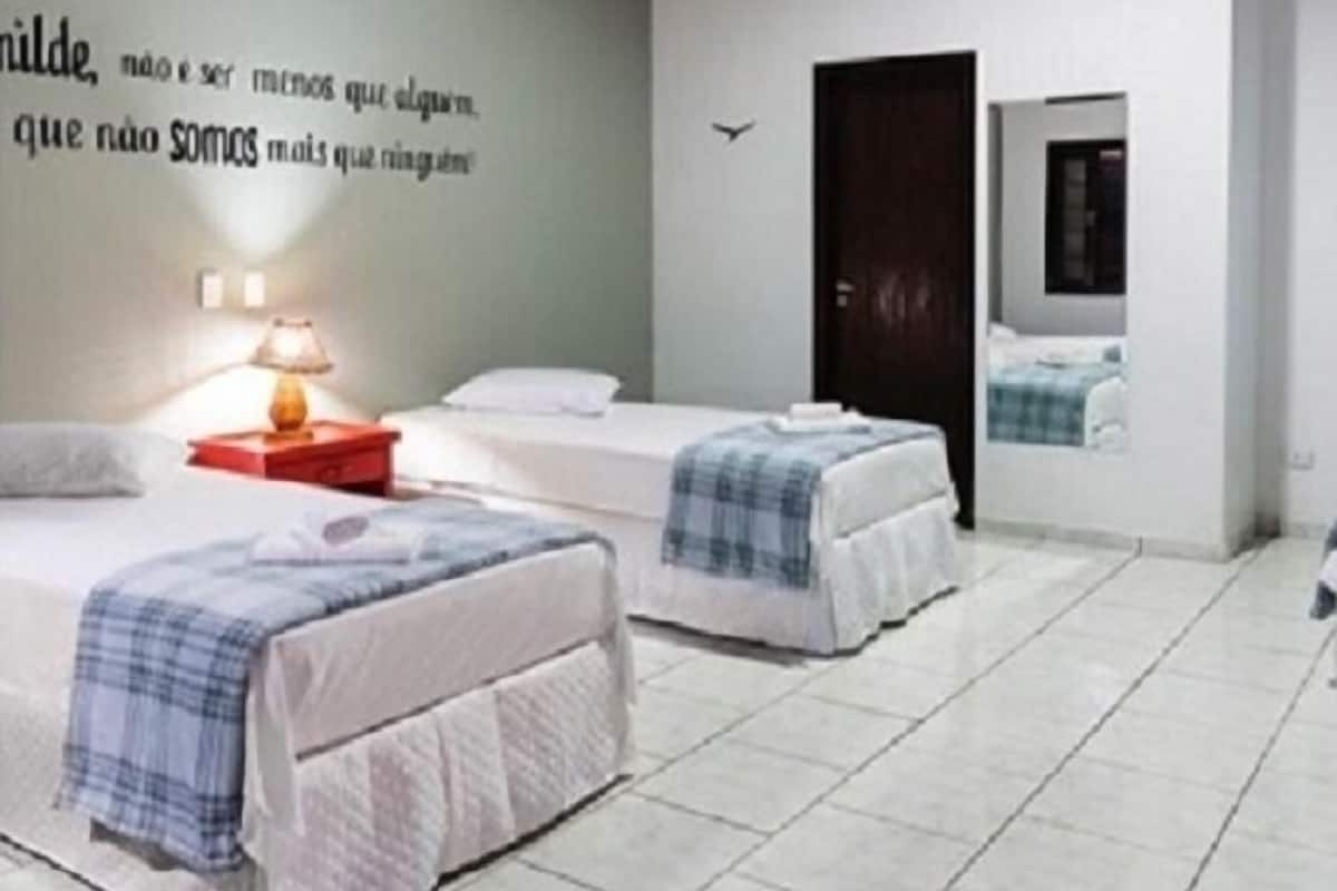 Een moderne hotelkamer met twee bedden, een houten plafond en een muur met een motiverende quote.