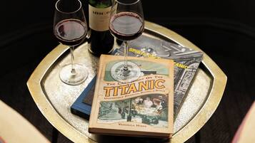 A tray with a book titled 'The Last Night on the Titanic' and two glasses of red wine.