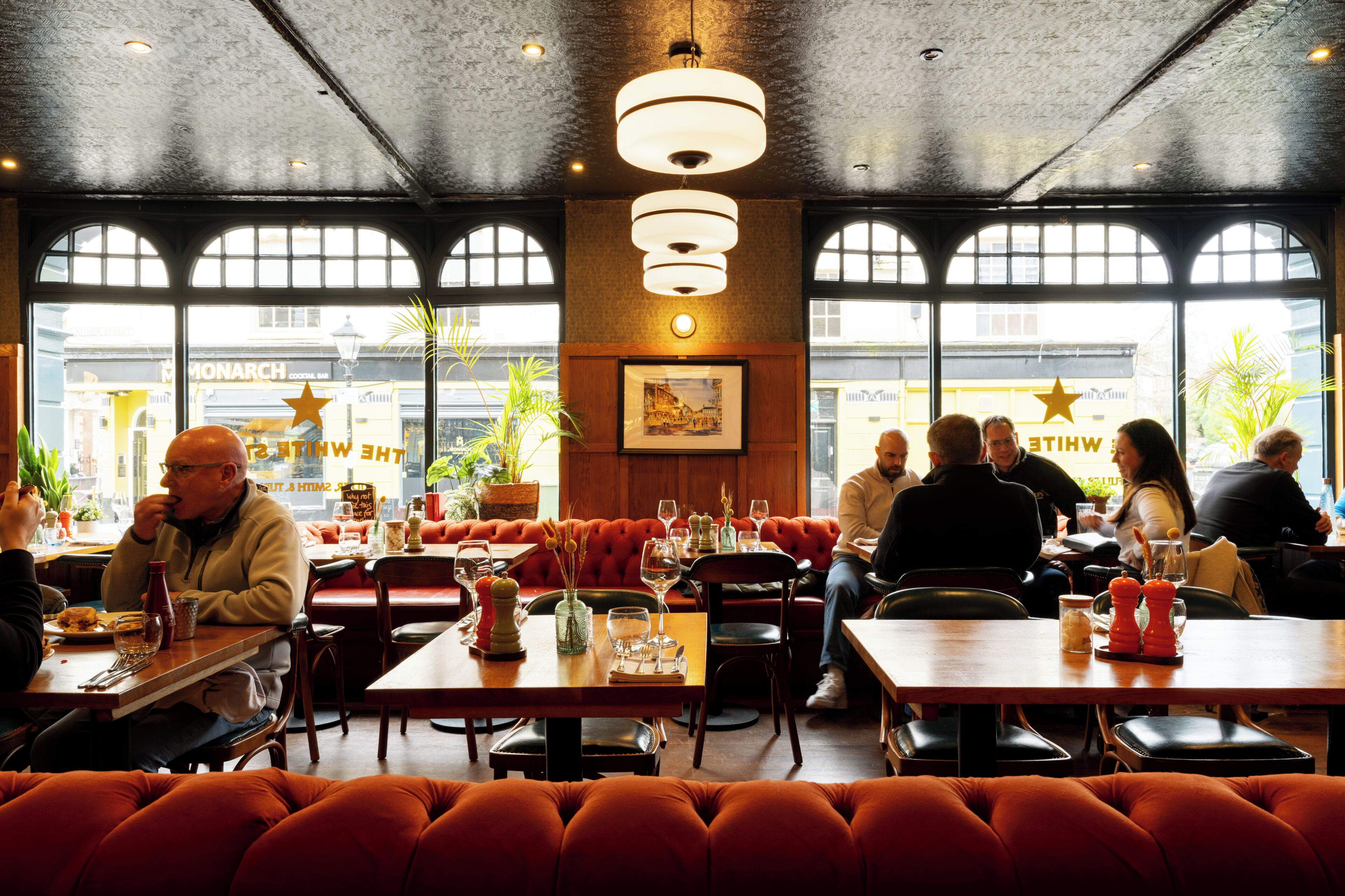 Un ristorante con tavoli, sedie e un'ampia vetrata che si affaccia sulla strada.