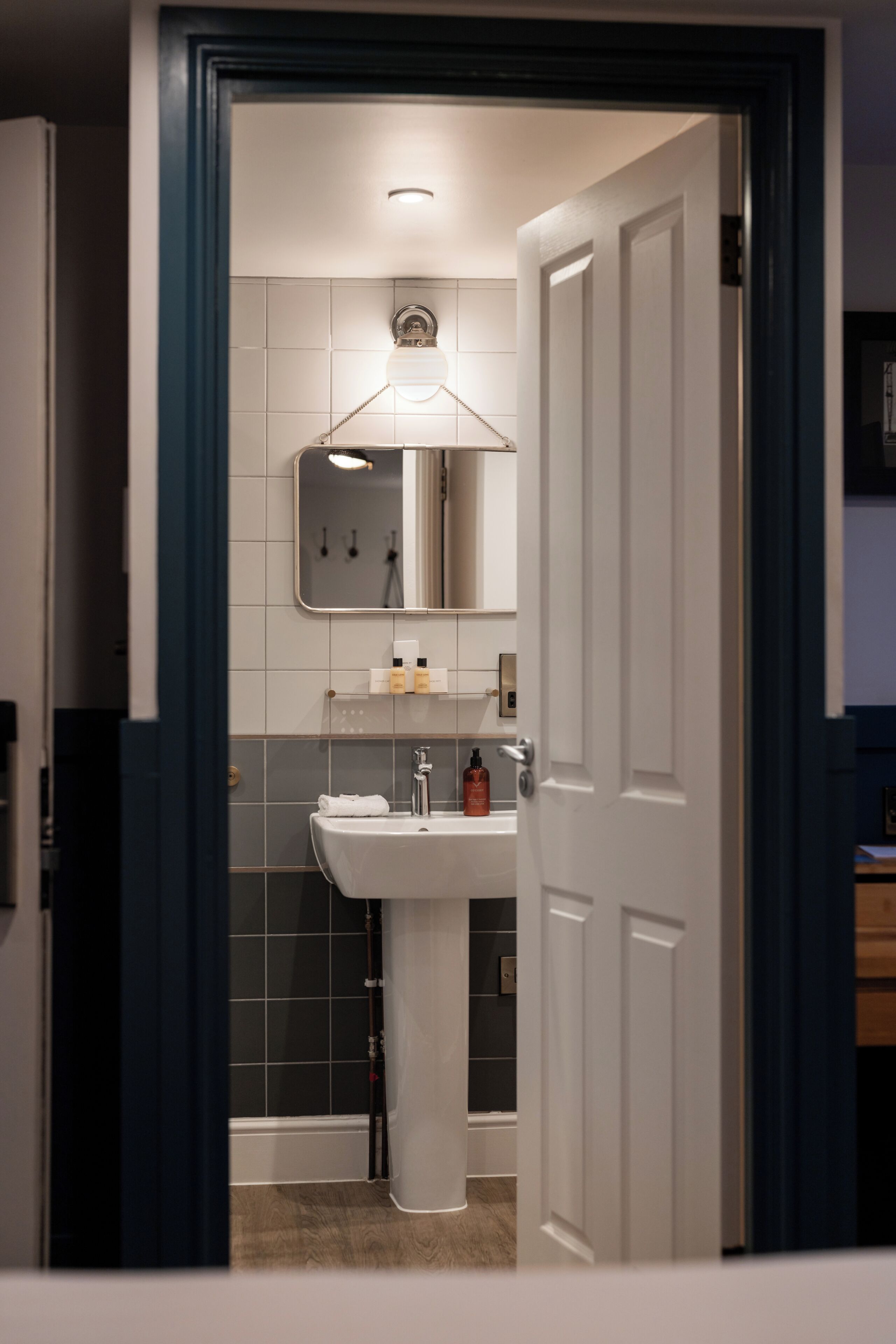 A bathroom with a white sink, mirror, and tiled walls.