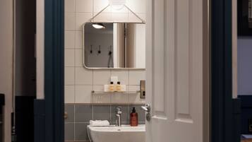 A bathroom with a white sink, mirror, and tiled walls.