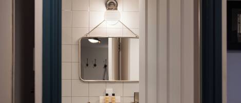 A bathroom with a white sink, mirror, and tiled walls.