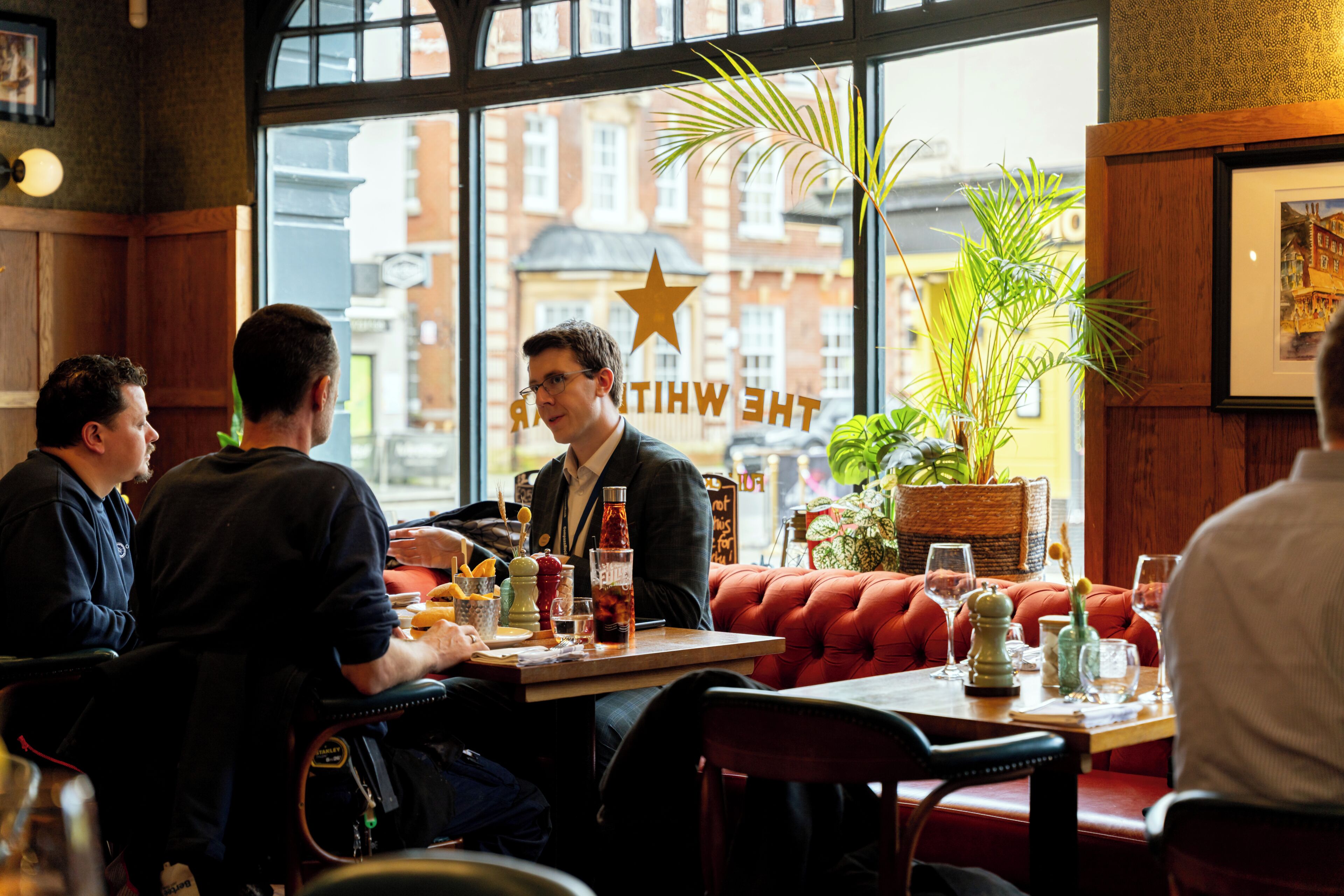 A restaurant with wooden furniture, a large window with a view of buildings, and a star decoration on the wall.