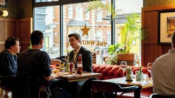 A restaurant with wooden furniture, a large window with a view of buildings, and a star decoration on the wall.
