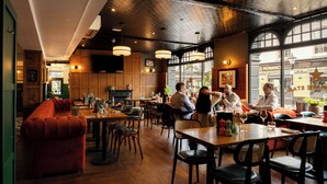 Un restaurante con mobiliario de madera, chimenea y ventanas amplias.