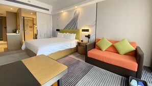 A hotel room with a bed, a sofa, a desk, and a shower area. - Hampton by Hilton Guangzhou Zhujiang New Town (Guangzhou)