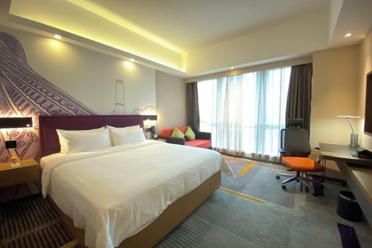 Una habitación de hotel con una cama grande, un escritorio, una silla y un televisor.